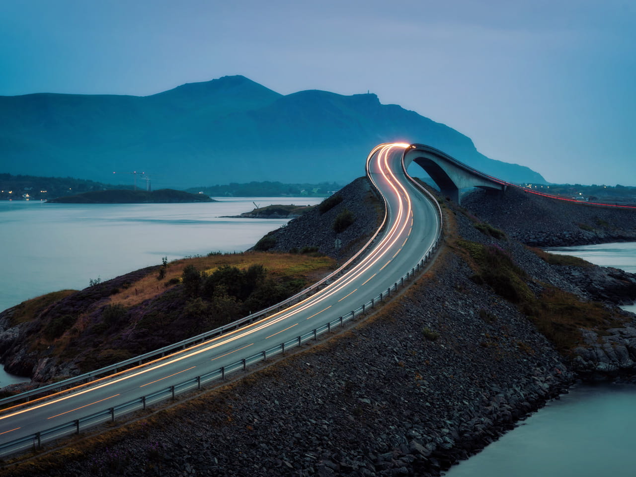 A scenic winding road along a mountainside with a lake below.